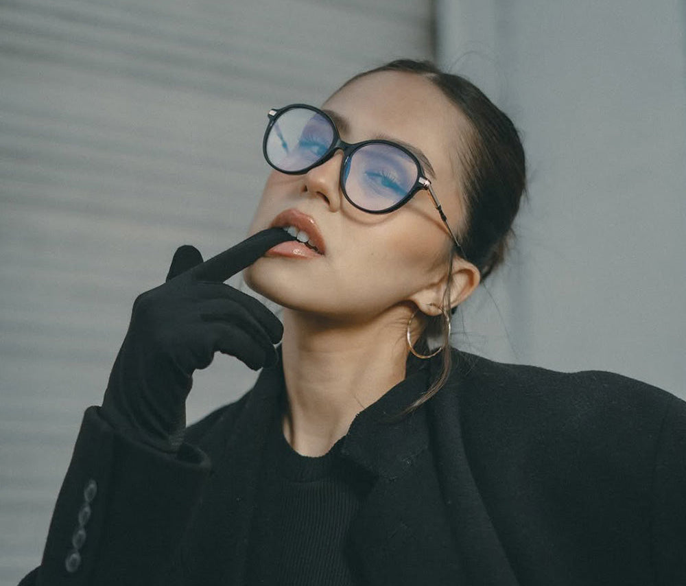 Person wearing black coat and gloves, with a neutral background