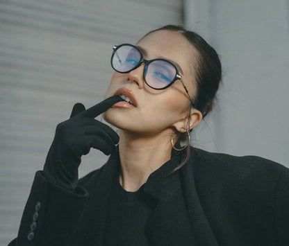 Person wearing black coat and gloves, with a neutral background