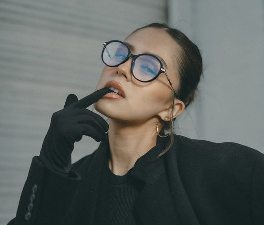 Person wearing black coat and gloves, with a neutral background